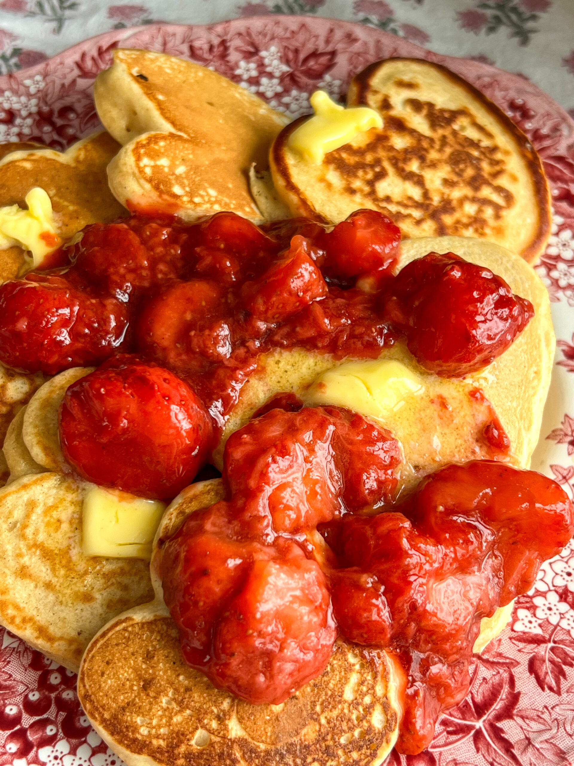 strawberry sauce and butter slathered on heart pancakes