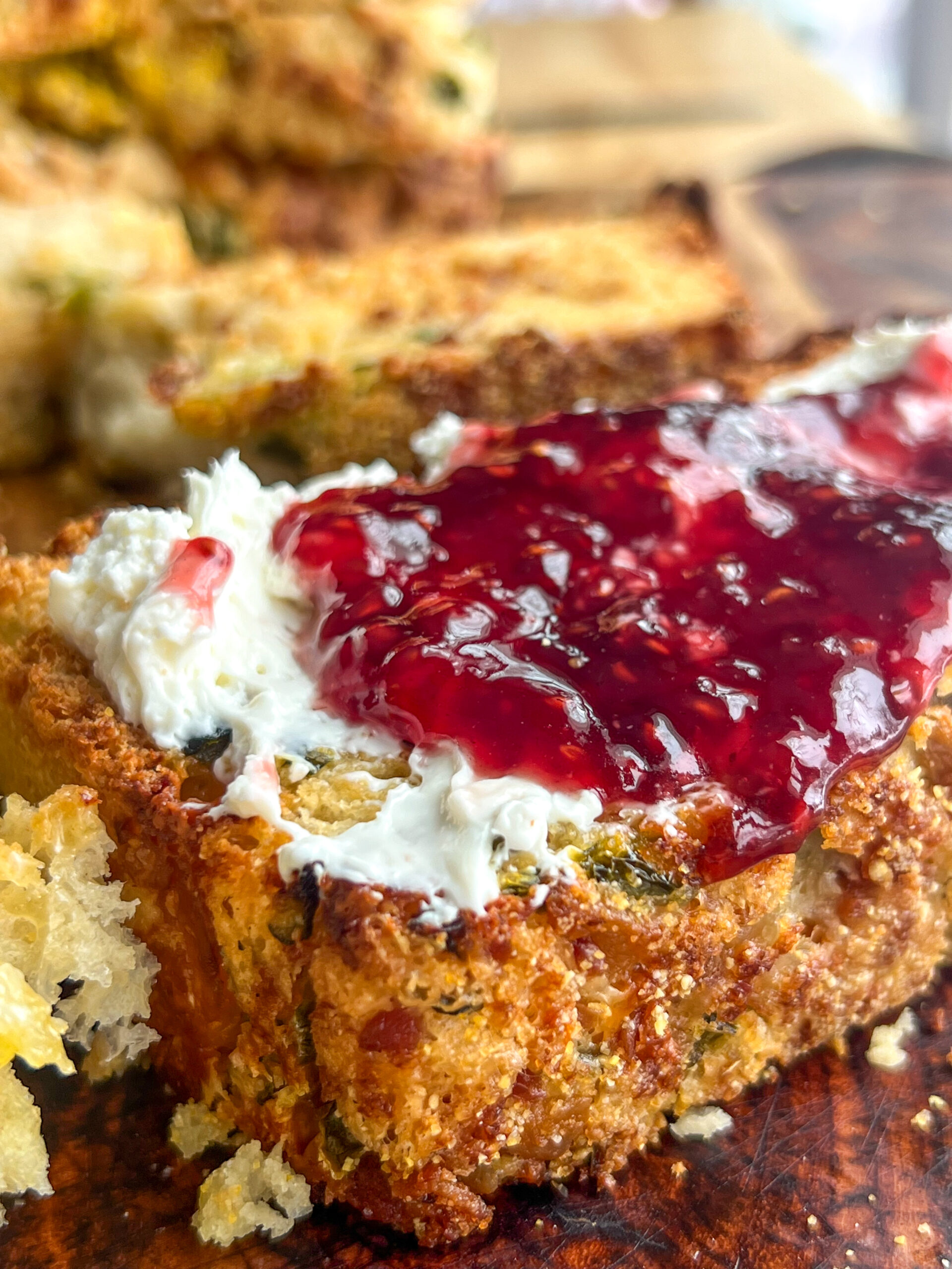 close of golden brown jalapeno popper english muffin bread topped with cream cheese and jam