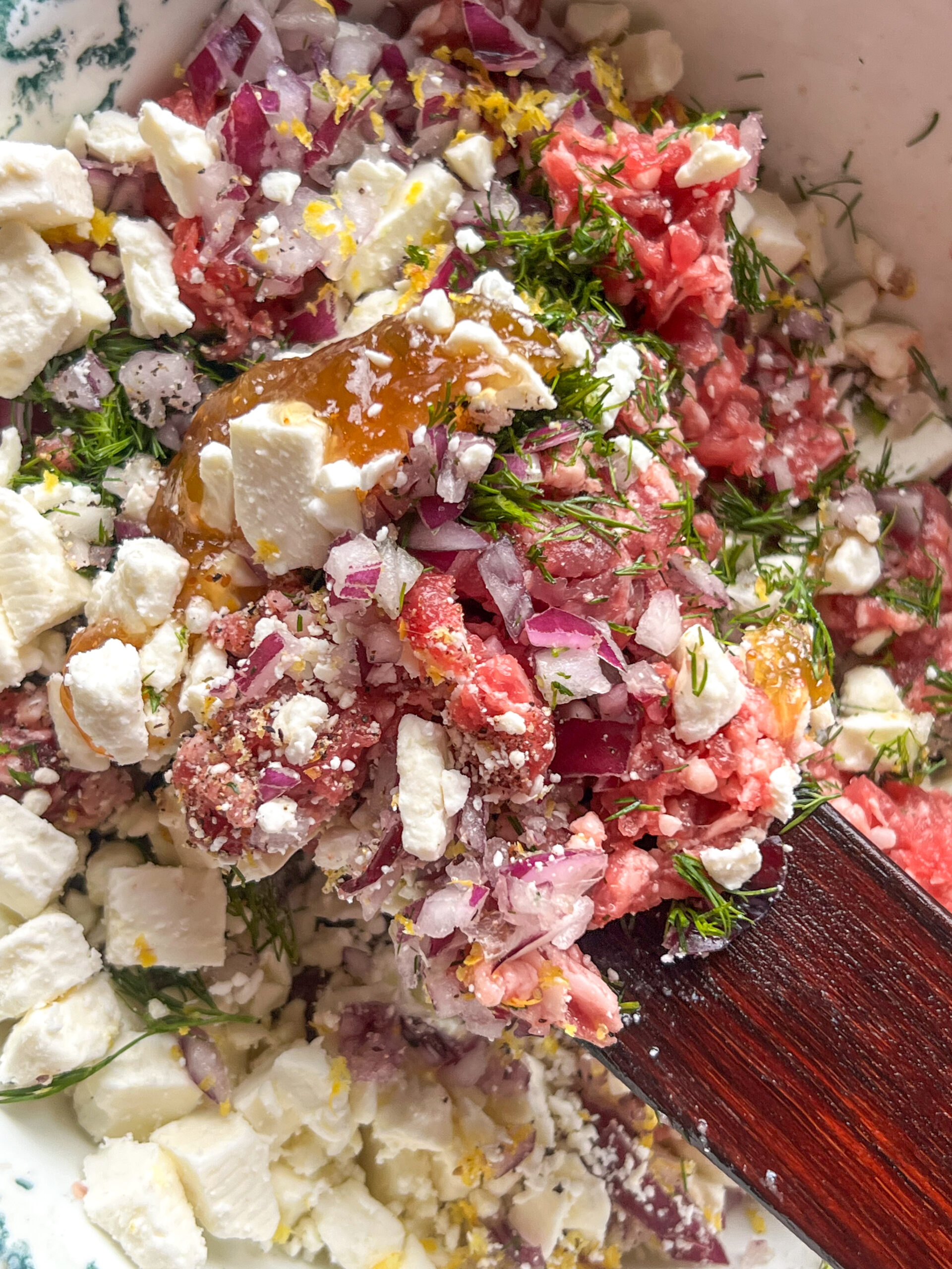 fig and feta lamb burger being mixed together with wooden spatula