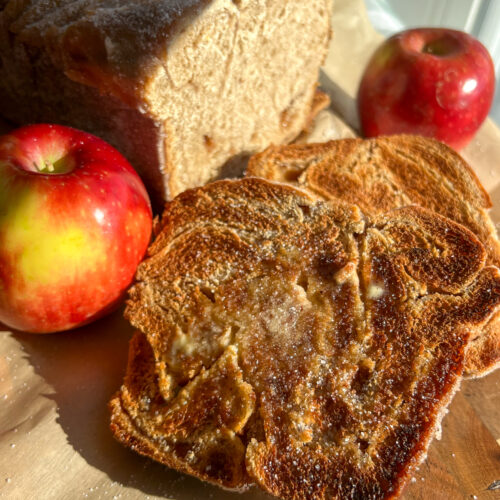 Apple cider donut bread slices on cutting board with apples