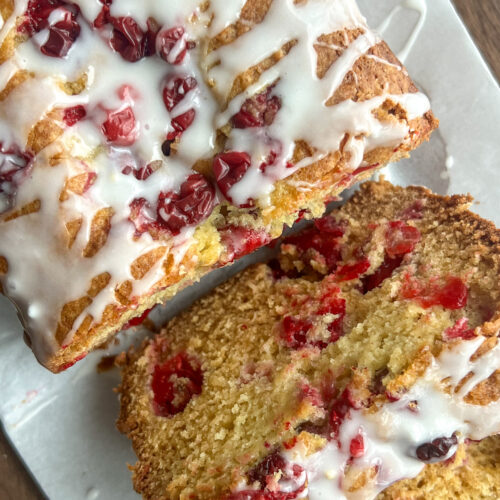 Eggnog Cranberry Holiday Loaf Cake with an eggnog glaze on a white platter