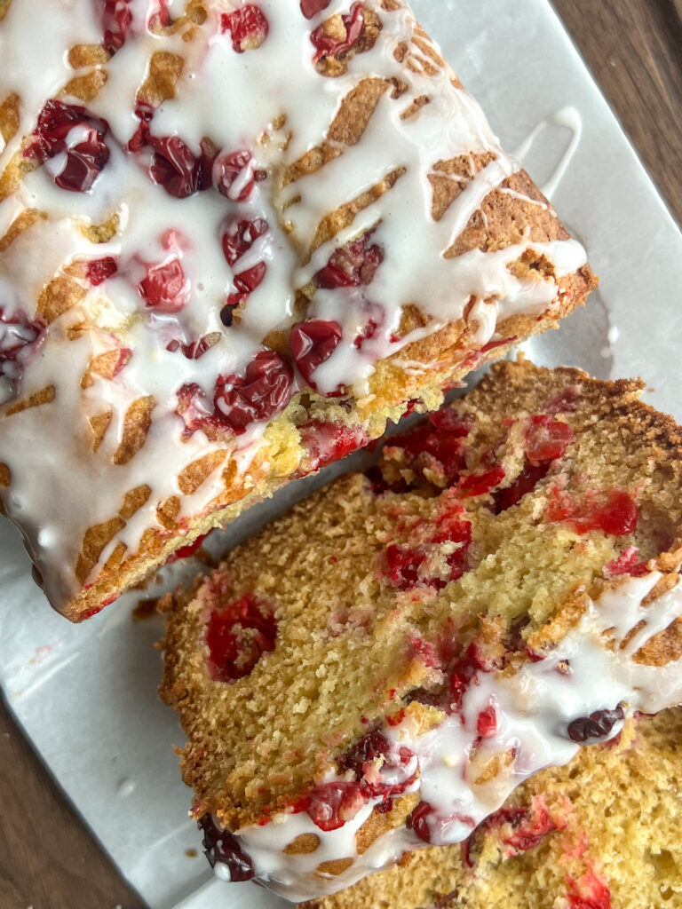 Eggnog Cranberry Holiday Loaf Cake with an eggnog glaze on a white platter