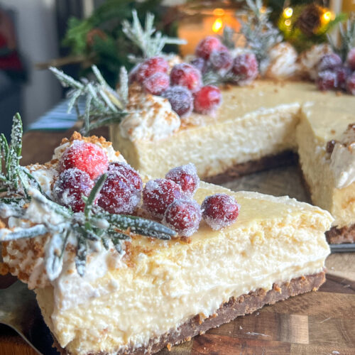 Eggnog Cheesecake with Gingerbread Crust topped with sugared cranberries and rosemary