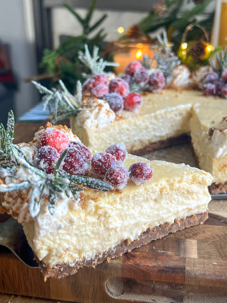 Eggnog Cheesecake with Gingerbread Crust topped with sugared cranberries and rosemary